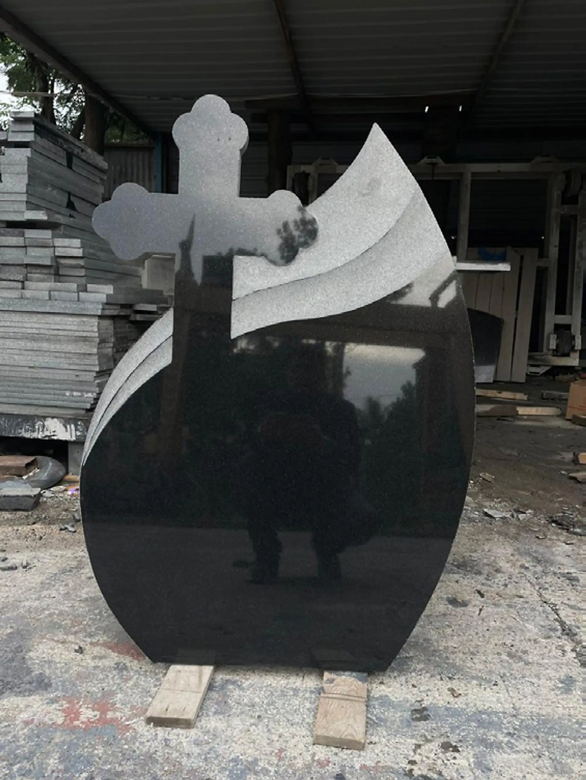 Polished black granite monument with a carved cross