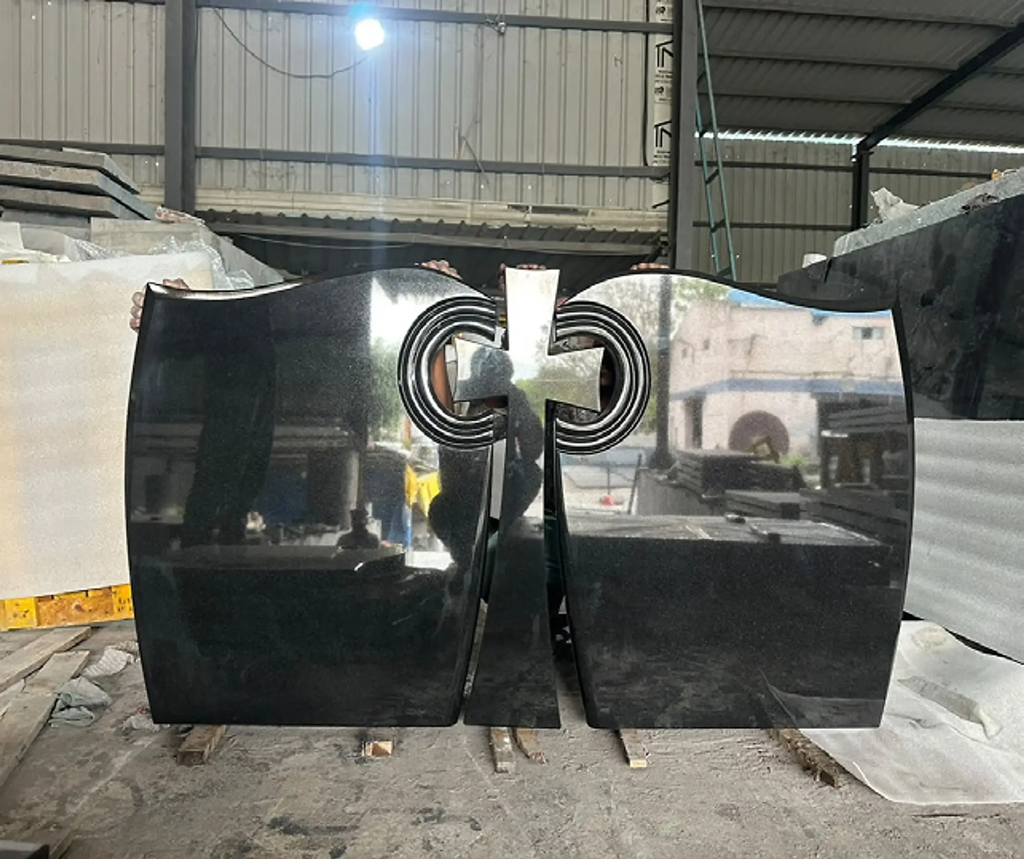 Polished black granite double memorial with a carved centrepiece