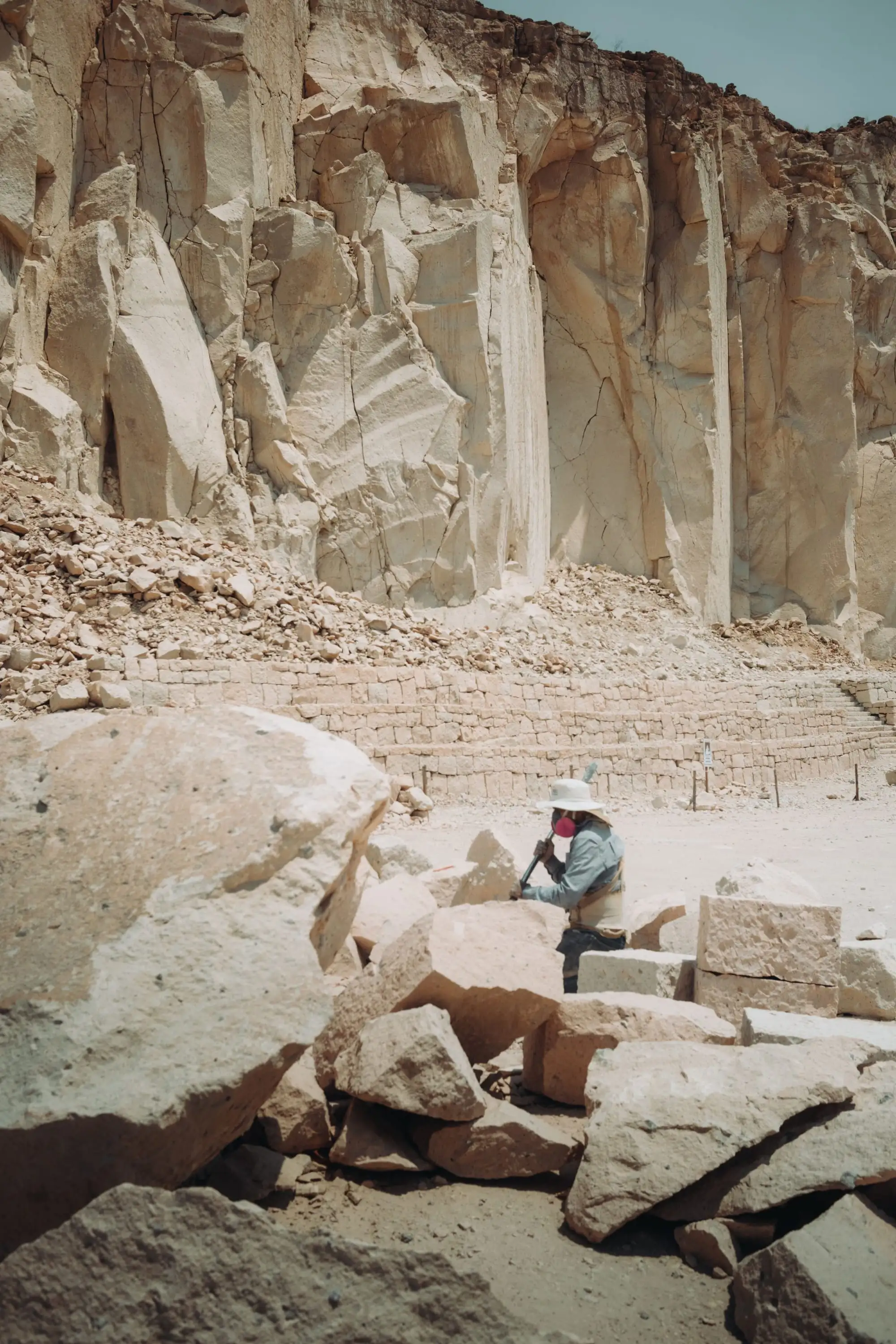 A lone worker among large rocks in a quarry